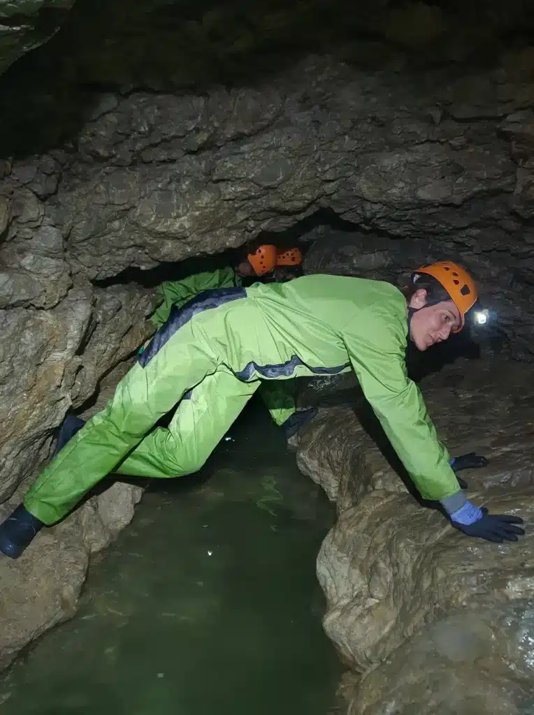 Spéléologue qui passe en opposition au dessus de l'eau lors d'une sortie de spéléologie du Dévoluy