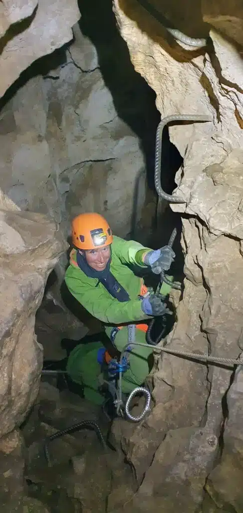 Une personne en tenu de spéléologie remonte de la Via Souterrata de la Tune-min