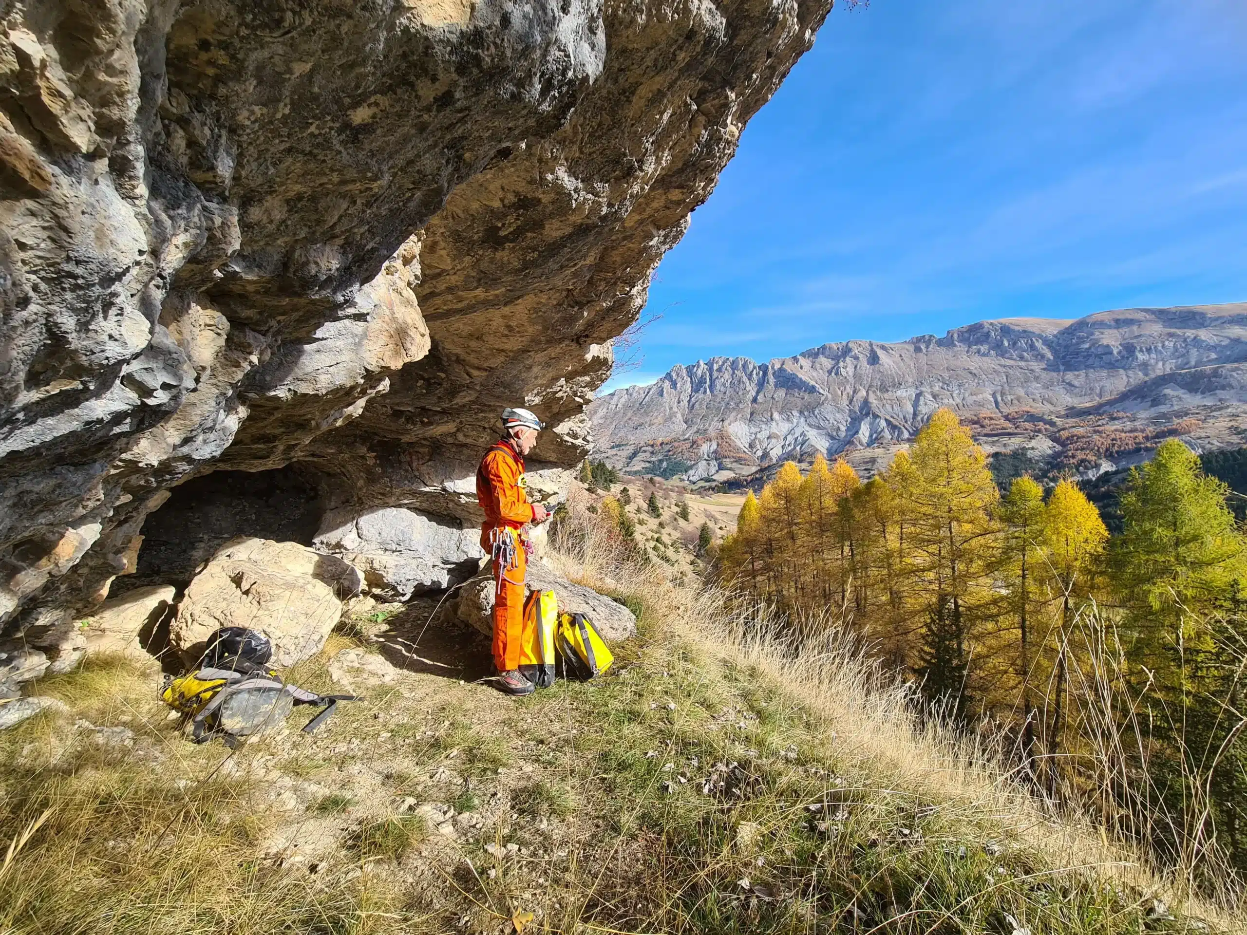 Un spéléologue regarde le paysage devant l'entrée de la grotte des Baumettes