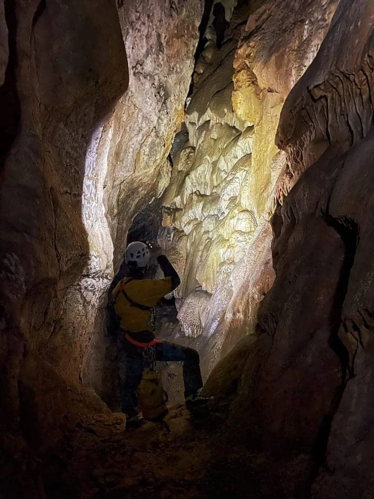 Une personne éclaire devant lui une grande galerie souterraine de la montagne de Céüse