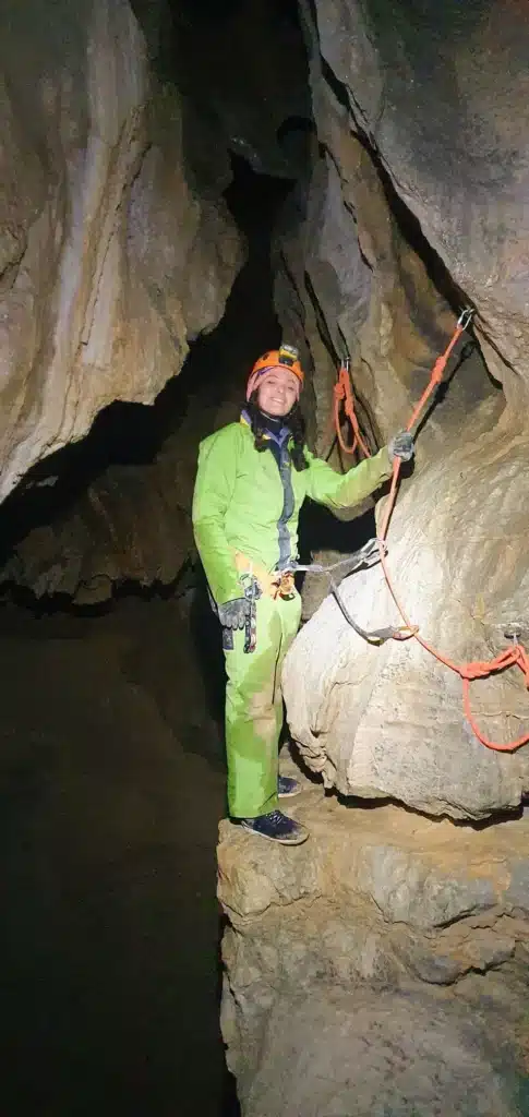 une personne en tenue de spéléologie s'accroche à une corde à l'aide de son harnais de sécurité dans la grotte de la Résurrection située dans les gorges d'Agnielles
