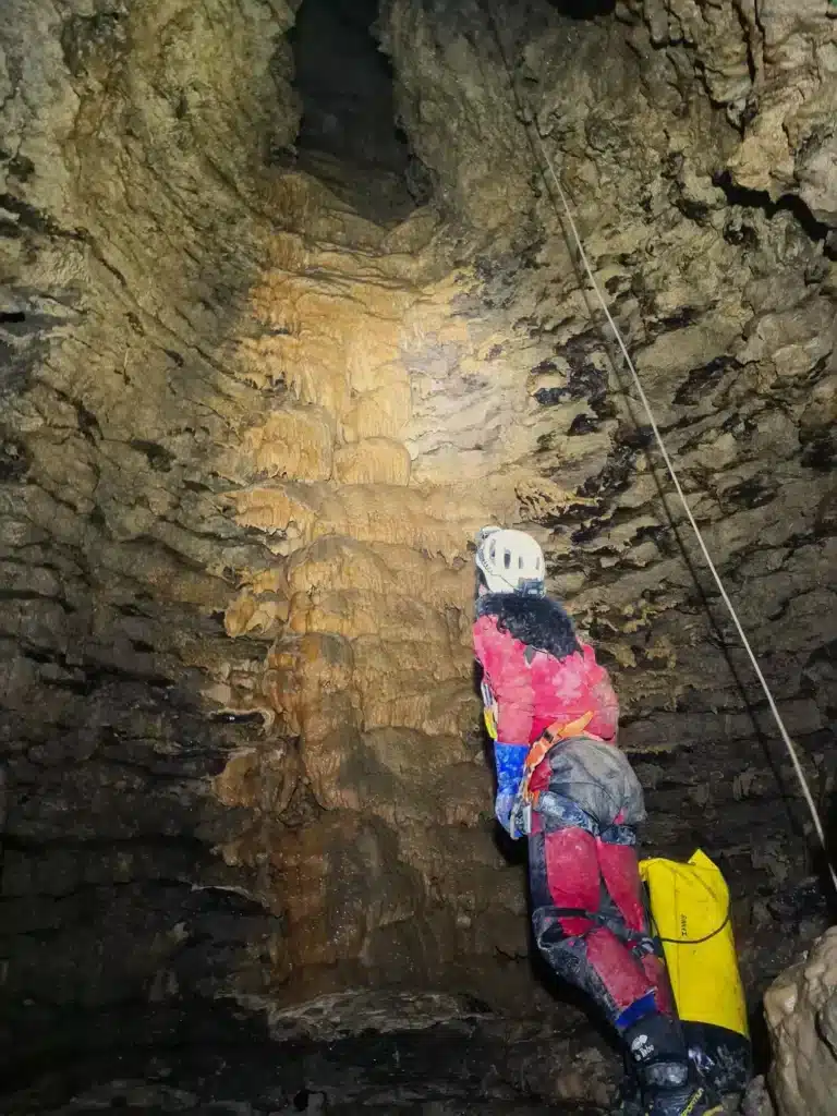 Une personne eclaire avec sa lampe frontale un puits souterrain d'une grotte à SuperDévoluy