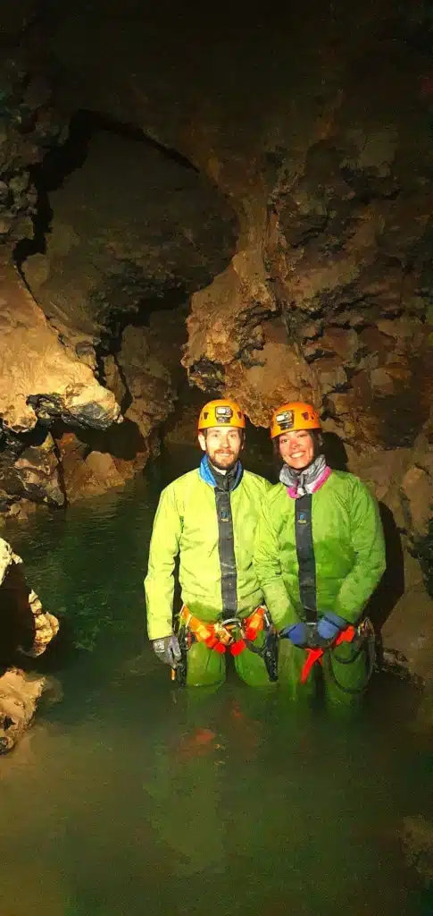 deux personnes équipés d'une tenue de spéléologie se tiennent debout dans un lac souterrain du Puits des Bans
