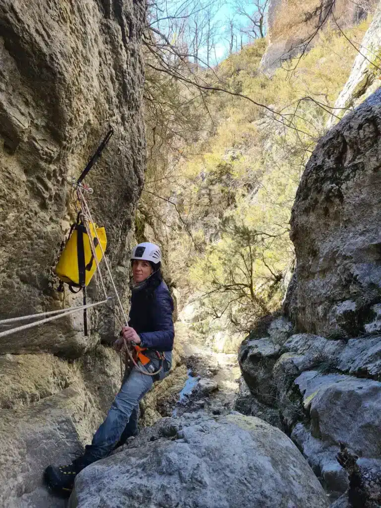 Une dame se sécurise à l'aide de son baudrier au sommet d'une cascade en canyoning de Rosans