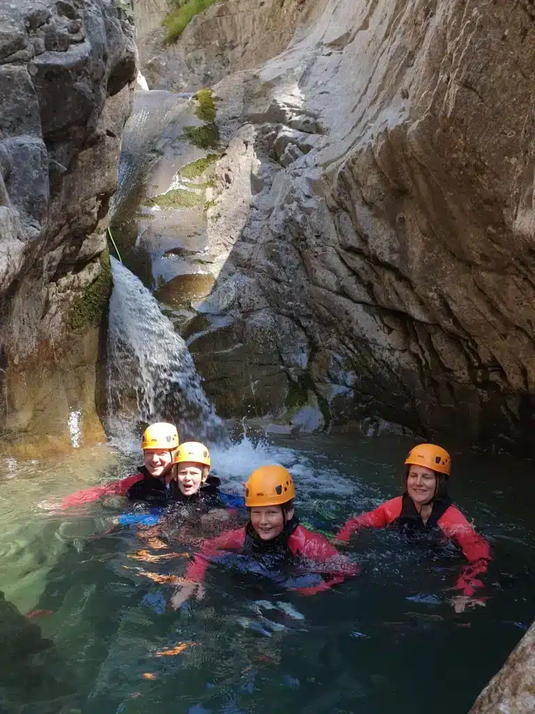 quatre personnes nagent dans une vasque naturelle équipée en tenue de canyoning à Gap