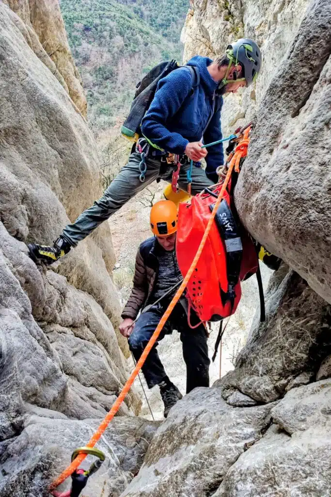 Deux canyonistes équipés de casques et de baudriers descendent dans un canyon étroit du village de Orpierre, en s'aidant de cordes et de matériel d'escalade.