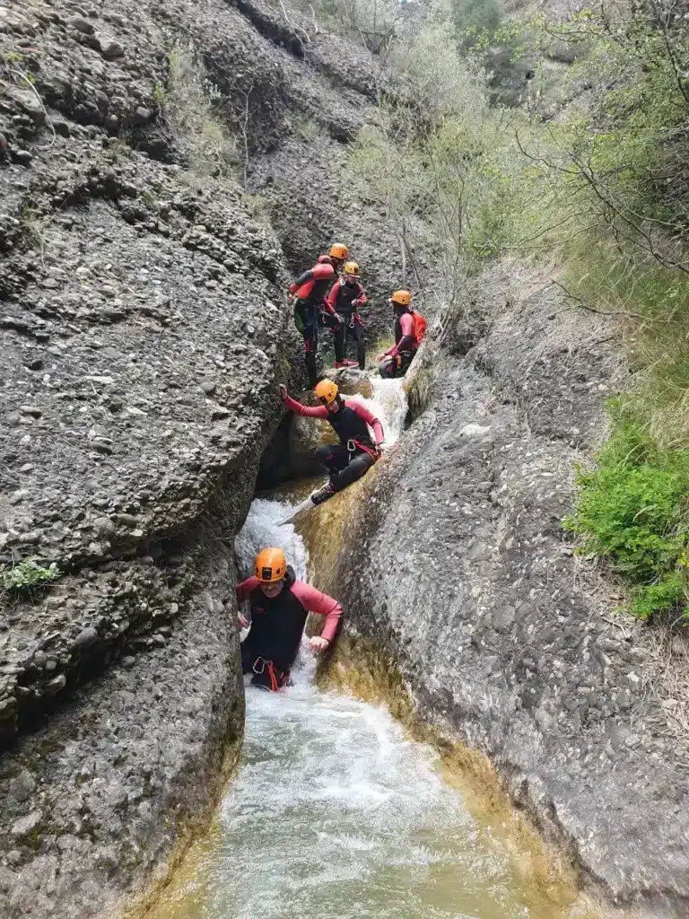 Groupe de personnes en combinaison et casque descendant une rivière dans un canyon du Dévoluy qui est étroit.