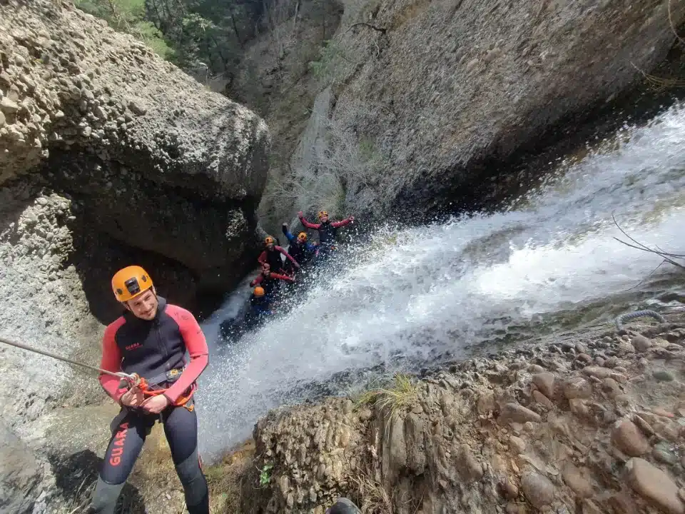 Groupe de canyonistes en combinaison s'apprêtant à descendre en rappel dans une cascade dans un canyon du Dévoluy.