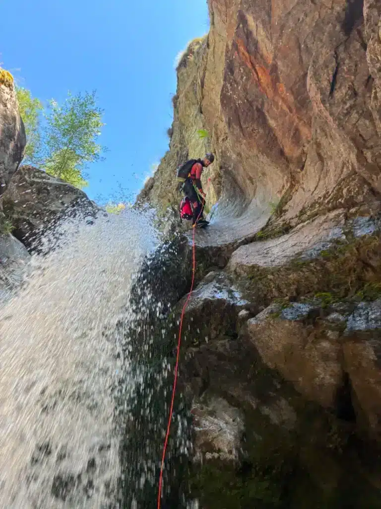 Une personne descend en rappel une cascade, dans un canyon étroit dans la vallée de Orcières Merlette.